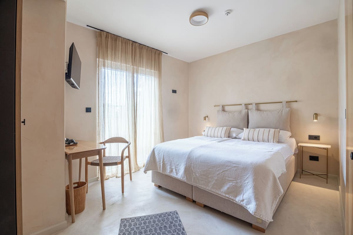 A bedroom with a bed, bedside tables, a desk, and a chair.