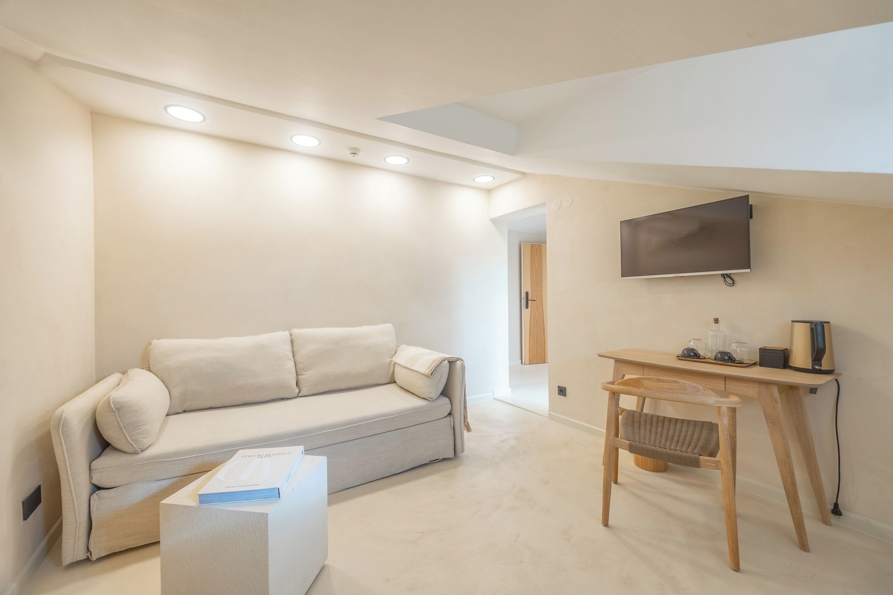 Een moderne woonkamer met een bank, een houten tafel en een flatscreen televisie aan de muur.