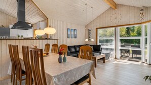 Una habitació àmplia amb taula de menjador, cadires, sofà i un gran finestral.