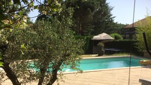 A wooden deck with a pool, a bench, and a hanging swing. - Maison, Piscine Privée et Terrain de Boules, au Calme (Trévoux)