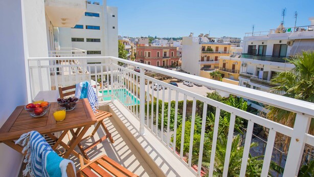 Un balcón con mesa lista para el desayuno, una piscina y vistas a la ciudad.
