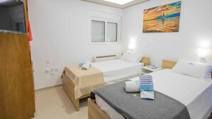 Habitación de hotel con dos camas, una ventana, un cuadro y un televisor.
