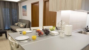Una cocina moderna con una isla grande, armarios blancos y un área de comedor con sofá y sillas.