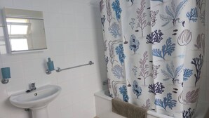 Een badkamer met een wit wastafel, een handdoekhouder en een douchegordijn met een patroon van blauwe en paarse planten.