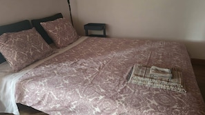 A bed with a patterned bedspread, two pillows, and a folded blanket.