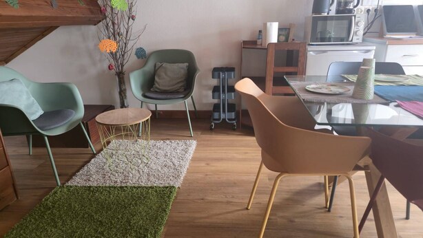 Een moderne woonruimte met een eethoek, een keuken en een zithoek met stoelen en een tafel.