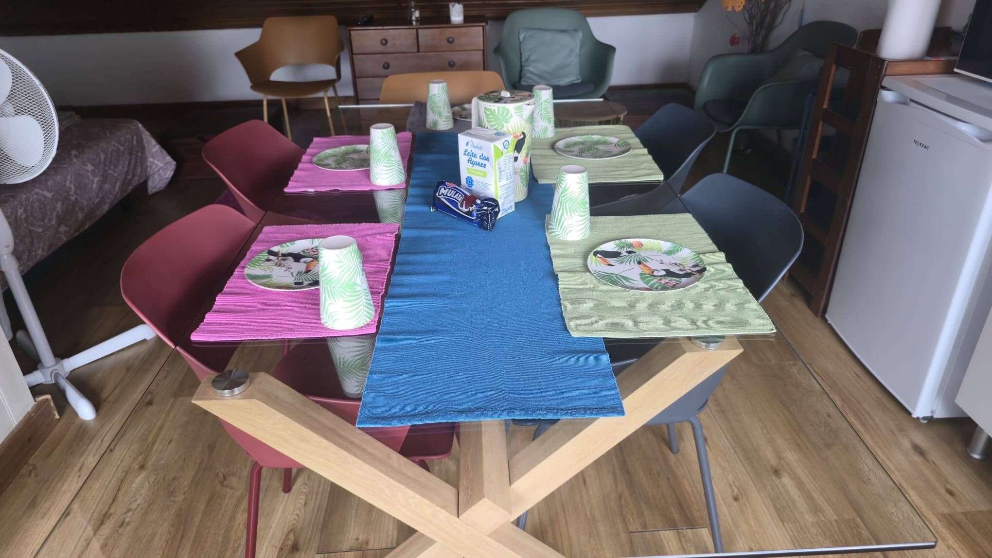 A dining table set with plates, cups, and a box of milk.