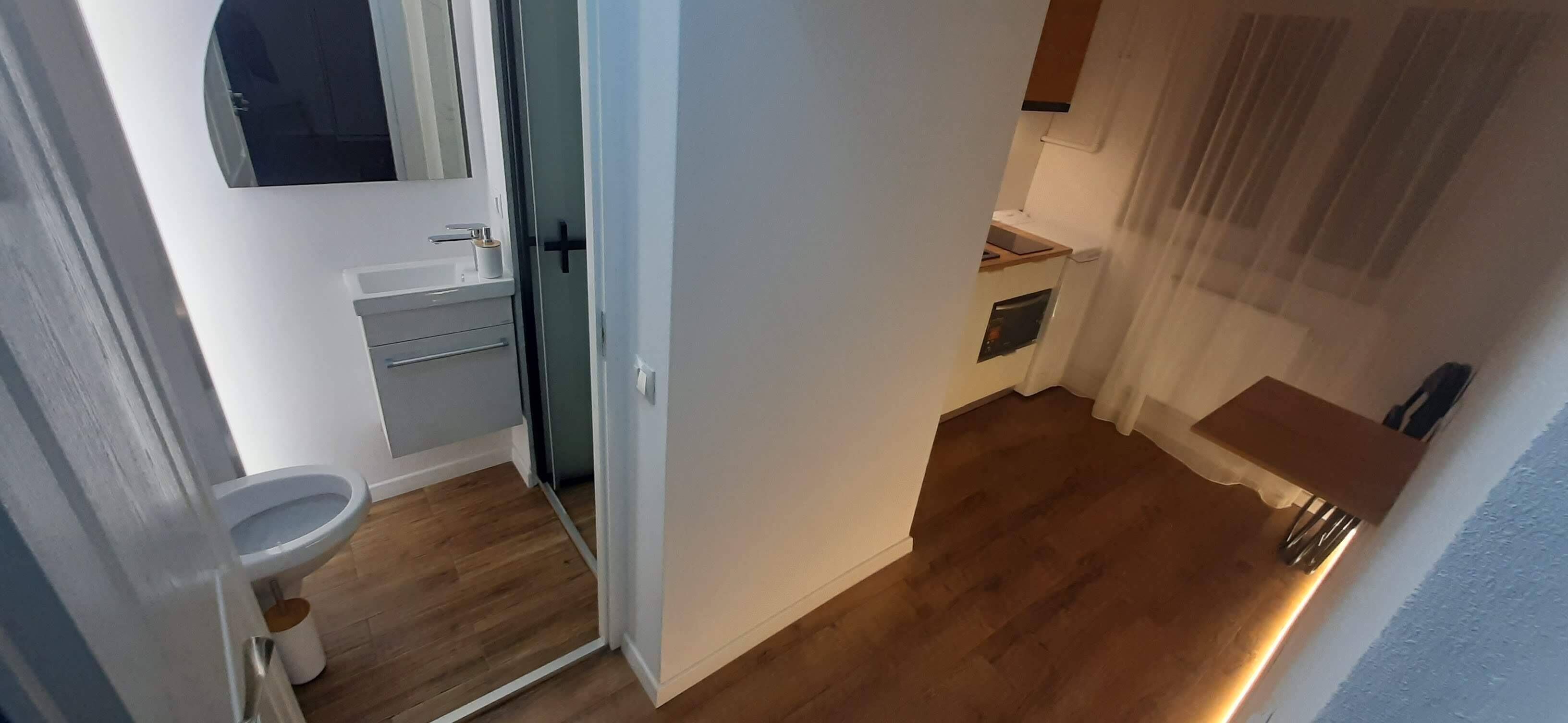 A narrow hallway with a toilet, a sink, and a small window.