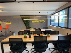 Uma sala de conferência moderna com uma mesa comprida, cadeiras de escritório pretas e um letreiro de neon na parede.