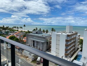 A coastal cityscape with modern buildings, a clear sky, and a view of the ocean.