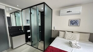 A hotel room with a bed, a red throw, a wall-mounted air conditioner, a telephone, and a framed picture. - Bela Hospedagem - Get One Bessa (João Pessoa)