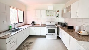 A modern kitchen with white cabinets, a built-in oven, a microwave, and a coffee maker. - 2BR/2BR w/Rooftop Terrace, steps from the Beach, Tamarindo Condo (Tamarindo)