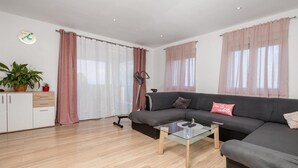 Una sala de estar moderna con un sofá, una mesa de centro de vidrio y un mueble con plantas.