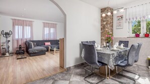 Una sala moderna con un sofá gris, una mesa de comedor para cuatro comensales y una pared de acento de piedra.