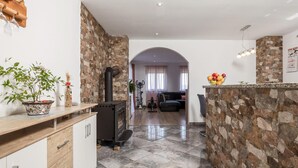Cocina moderna con pared de piedra, horno empotrado y zona de comedor con sofá y mesa.