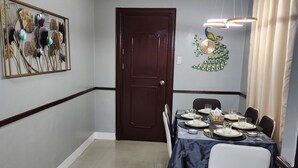 Un coin repas avec une table dressée pour quatre personnes, un ventilateur de plafond et un élément décoratif mural.
