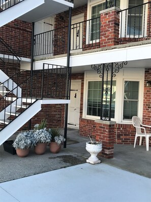 Stylish two-story building with a white exterior, black railings, and a charming entrance.