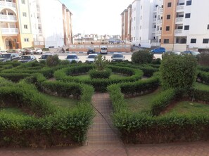 Stroll through the beautifully manicured garden, lined with geometric hedges and a paved pathway.