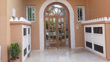 Stunning entrance with arched doorway, flanked by windows and a potted plant.