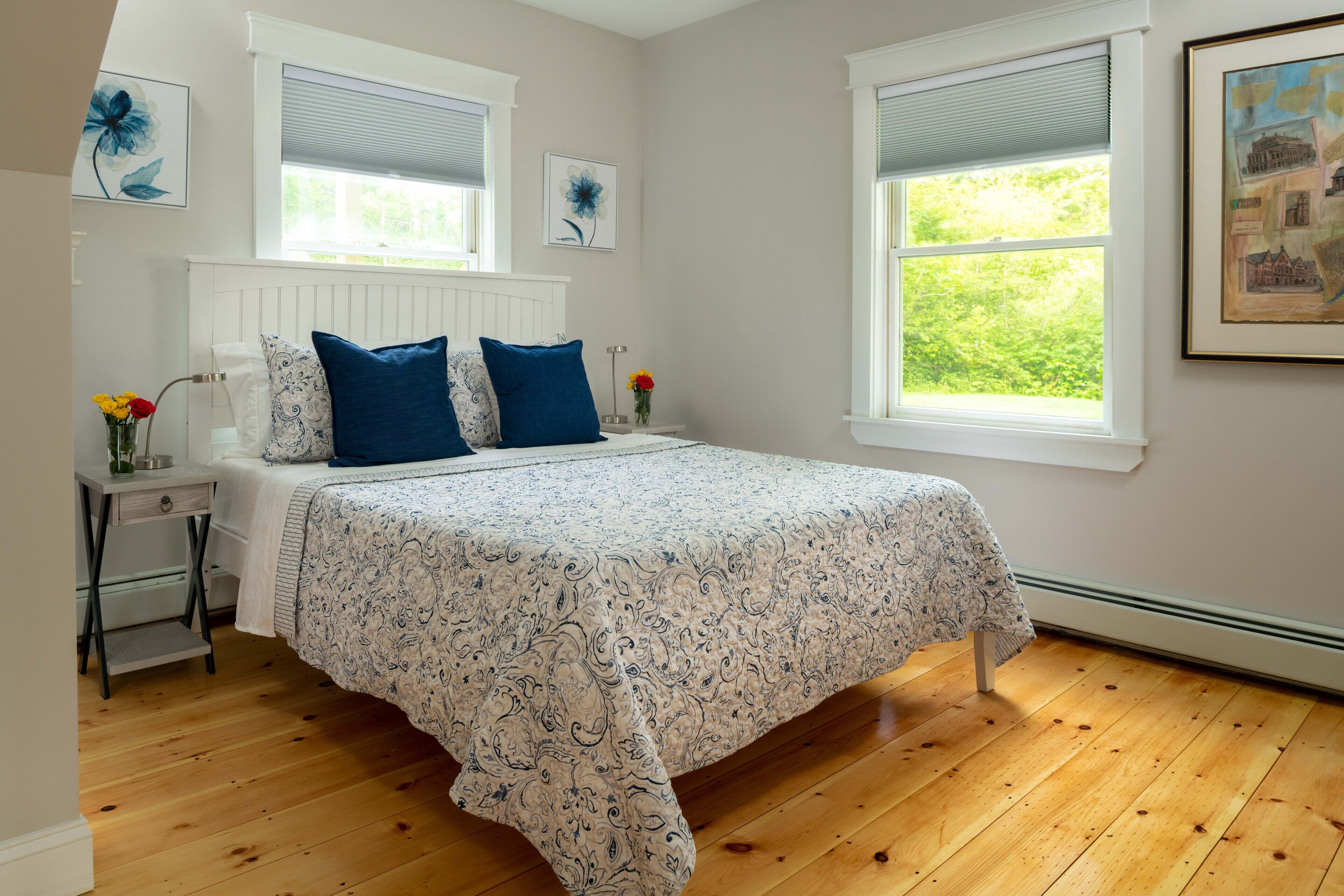 Un dormitorio con cama, mesita de noche, ventana y radiador.