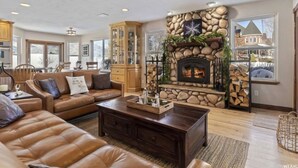 Una sala acogedora con chimenea de piedra, muebles de cuero y ventanas amplias.