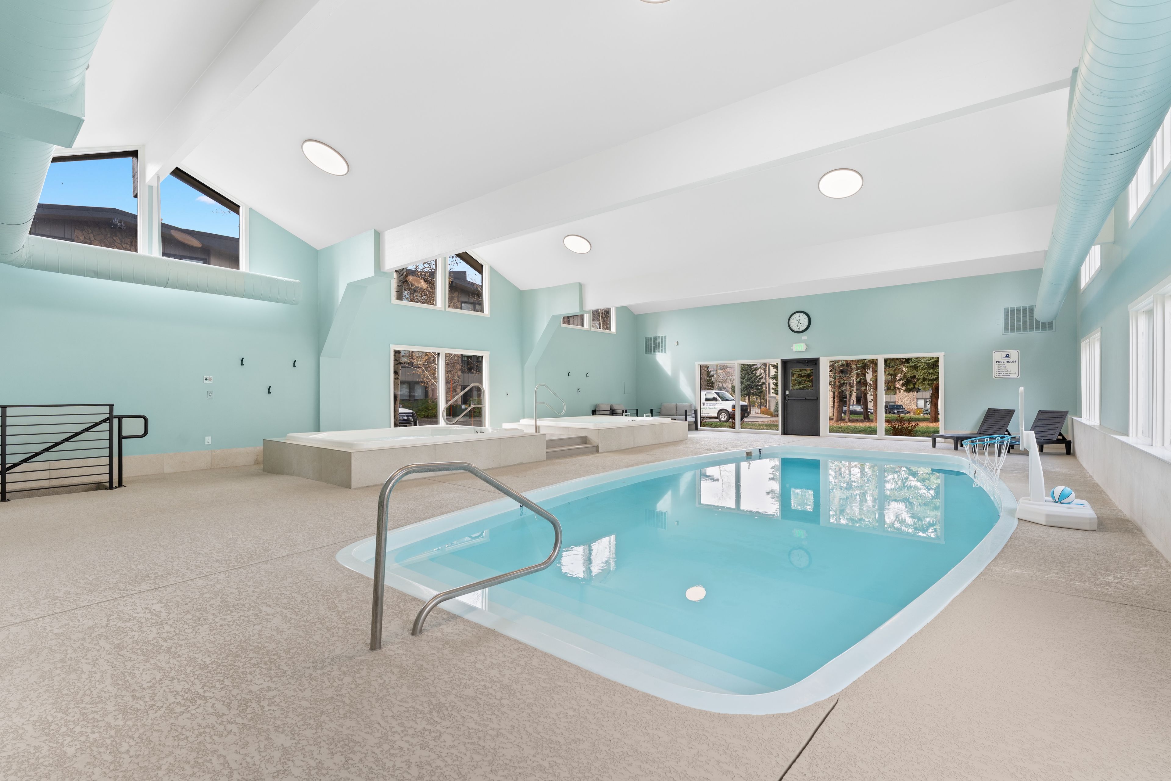 A large indoor swimming pool with a clear view of the outside through large windows.
