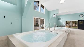 A spa area with two hot tubs, a view of the outside, and a clock on the wall.