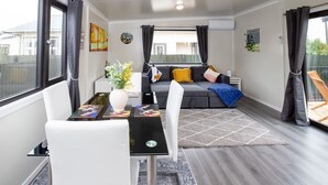 En moderne stue med en grå sofa, hvide lænestole, et sofabord og et tæppe.