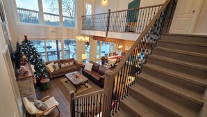 Un amplio salón con escaleras, ventanas grandes y un árbol de Navidad.