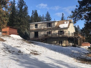 A two-story house with a balcony, surrounded by snow and pine trees. - Rocky Mountain Getaway (Plains)