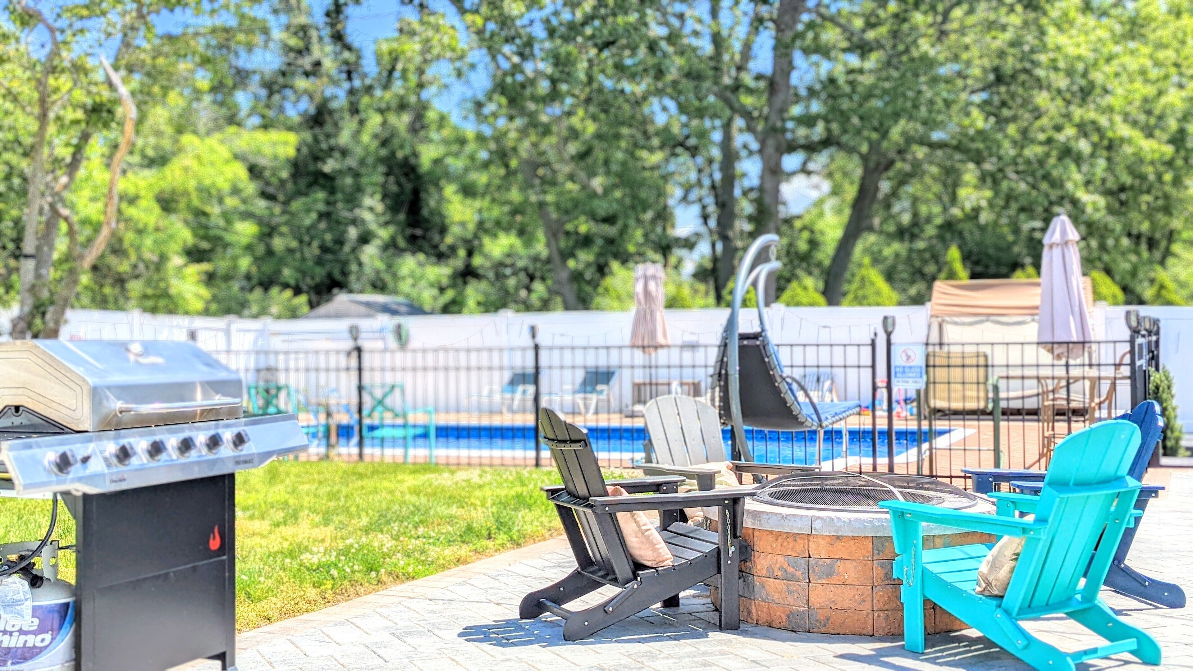 An outdoor patio with a grill, seating, and a pool.