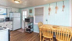 A kitchen with wooden cabinets, a refrigerator, a microwave, a stove, and a dining table with chairs.