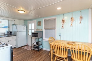 A kitchen with wooden cabinets, a refrigerator, a microwave, a stove, and a dining table with chairs.