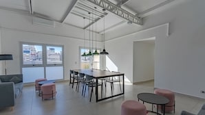 A spacious living area with a dining table, chairs, and ottomans. - Paseo de las Cisternas (Buenos Aires)