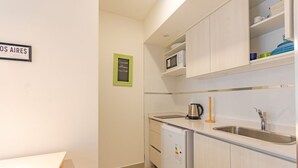 A compact kitchen with a sink, microwave, kettle, and a small refrigerator. - Paseo de las Cisternas (Buenos Aires)