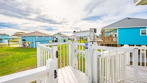A row of blue houses with white railings, a grassy yard, and a clear sky. - Beach Blessing with ocean view, 3br/2bath sleeps 8 (Bolivar Peninsula)