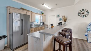 A modern kitchen with a large island, stainless steel appliances, and a decorative clock. - Beach Blessing with ocean view, 3br/2bath sleeps 8 (Bolivar Peninsula)