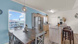 A modern kitchen with a wooden dining table, bar stools, and a built-in island. - Beach Blessing with ocean view, 3br/2bath sleeps 8 (Bolivar Peninsula)