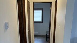 Un corridoio con pavimento in legno e pareti bianche, che conduce a una stanza con una finestra.