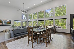 Amplia sala de estar con una gran mesa de comedor, múltiples sillas, un sofá y un ventilador de techo.