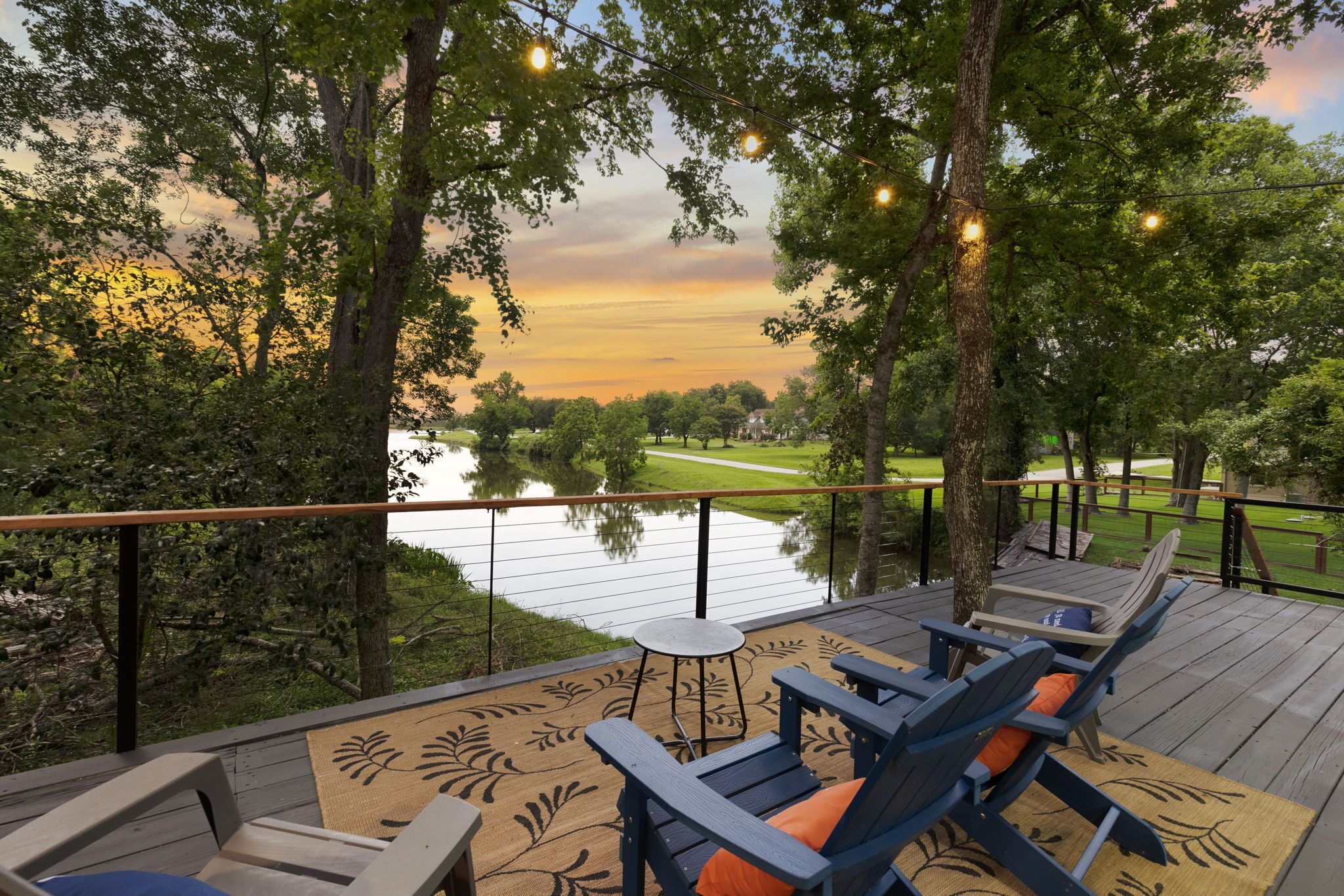 A deck with outdoor seating and a view of a lake at sunset.