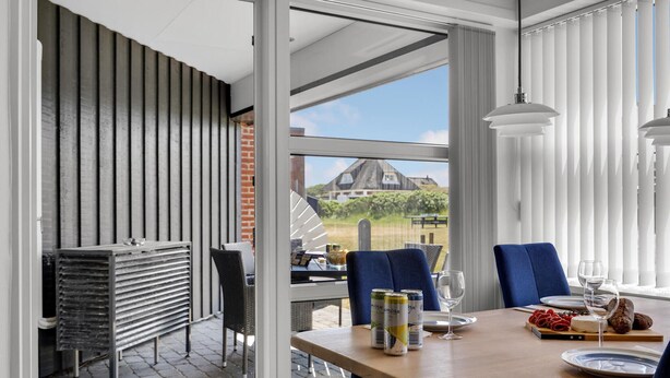 Un coin repas avec une table dressée pour deux personnes, une vue sur un vignoble et un aménagement intérieur moderne.