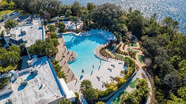 An aerial view of a resort with a large, curved swimming pool surrounded by lounge areas and a golf course. - Retreat 5 Bed Townhouse screened Private Pool*Amazing price (Davenport)