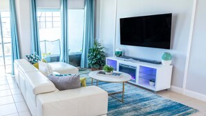 A modern living room with a white sofa, a coffee table, a flat-screen TV, and a potted plant. - Retreat 5 Bed Townhouse screened Private Pool*Amazing price (Davenport)