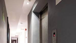 A hotel hallway with a modern elevator, a digital display showing the number 5, and a door marked with the number 53. - The Quay Hotel Bukit Bintang (Kuala Lumpur)