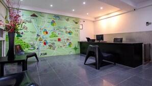 A reception area with a map on the wall, a desk, chairs, and a vase of flowers. - The Quay Hotel Bukit Bintang (Kuala Lumpur)