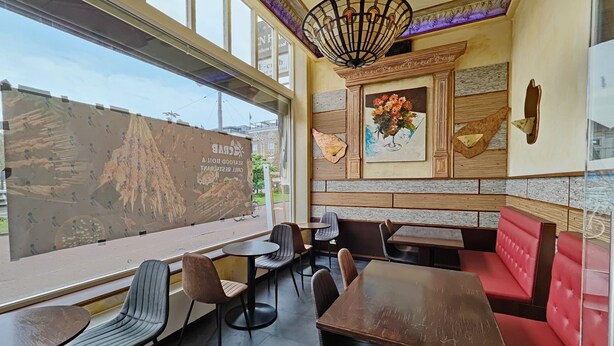 Un restaurante con un ventanal grande, paneles de madera y un mural en la pared.