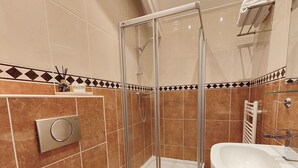 Un baño moderno con cabina de ducha de vidrio, lavabo e inodoro.