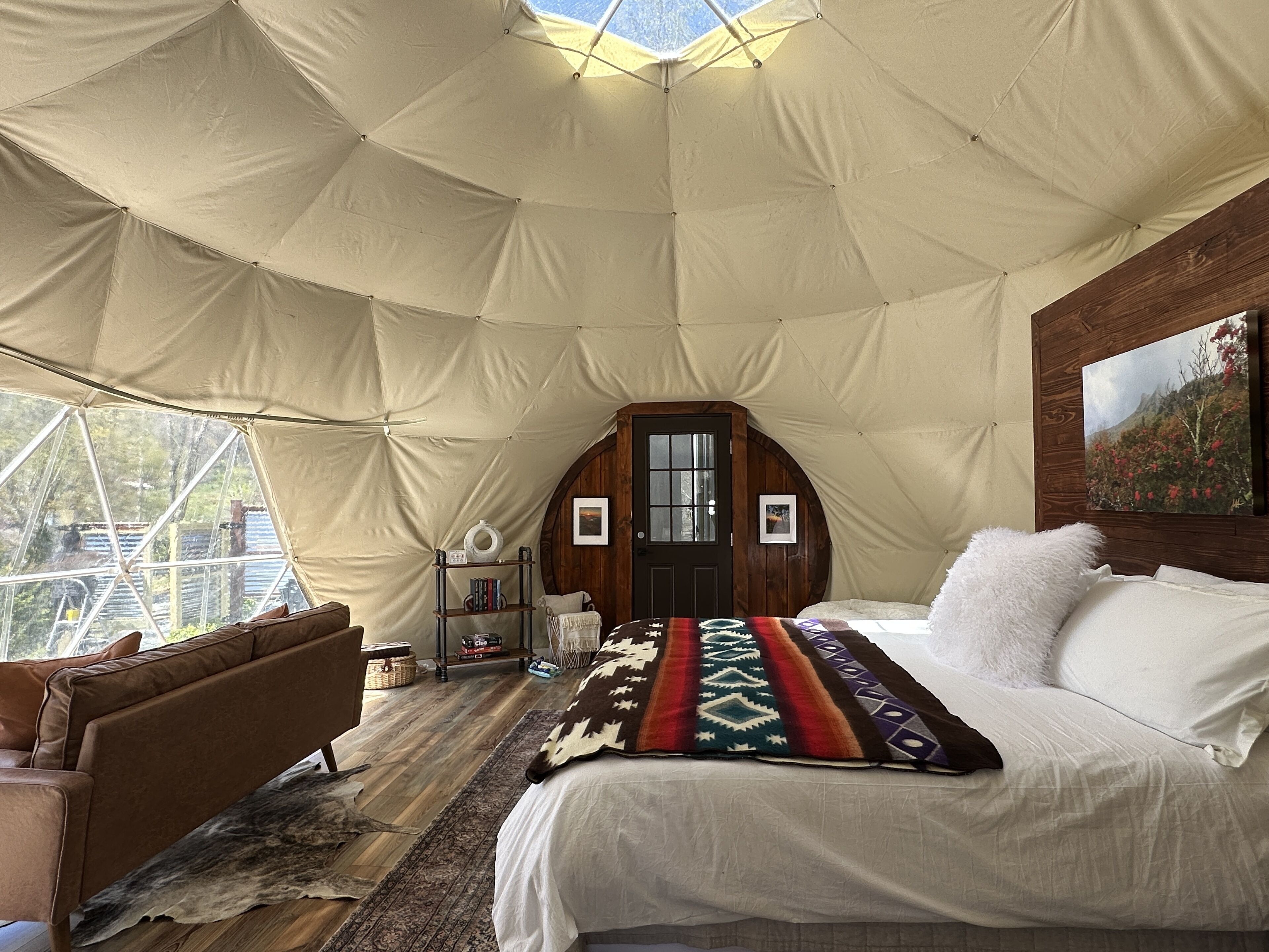 Una habitación con carpa, una cama, un sofá, una puerta de madera y una ventana.