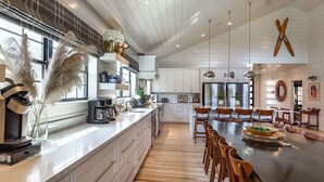 Una cocina amplia con una isla grande, sillas de madera y un comedor con mesa amplia.